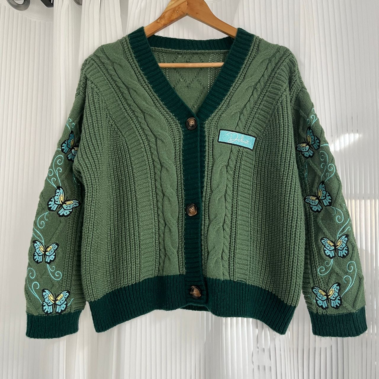 Taylor Swift inspired green cardigan with butterfly embroidered on both sleeves and a Debut patch with the albums font on the chest.