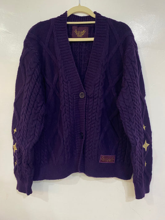 Purple cardigan with golden star patches on the sleeves and the album name Speak Now patch embroidered at the bottom.